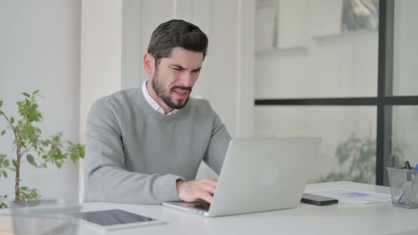 Unge mann med ryggsmerter mens han bruker Laptop i kontoret – stockvideo