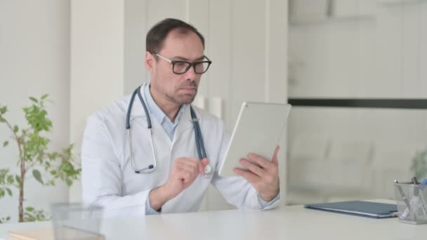 Μεσήλικας γιατρός Μιλώντας σε βίντεο κλήση στο Tablet στο γραφείο — Αρχείο Βίντεο