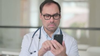 Orta yaşlı doktor akıllı telefon kullanıyor.