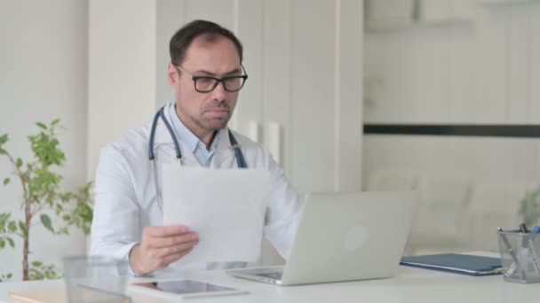 Medelålders läkare med bärbar dator läsning Dokument i Office — Stockvideo