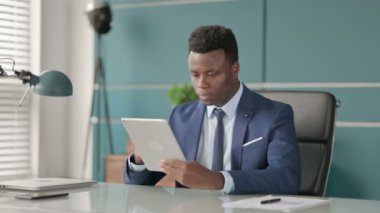 Ofiste otururken Tablet kullanan Afrikalı İşadamı