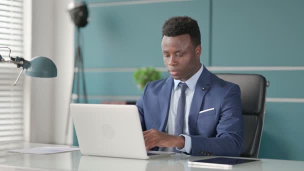 Empresario africano tosiendo mientras usa el ordenador portátil en la oficina — Vídeos de Stock