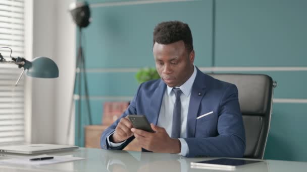 Успешный африканский человек празднует на смартфоне — стоковое видео