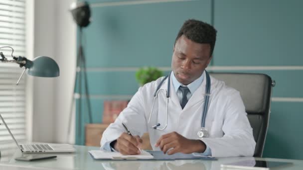 African Doctor Pisanie na papierze w biurze — Wideo stockowe