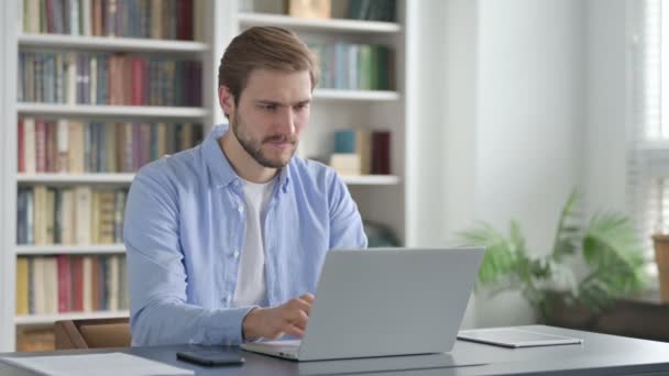 Людина святкує під час використання ноутбука в офісі на лавці — стокове відео