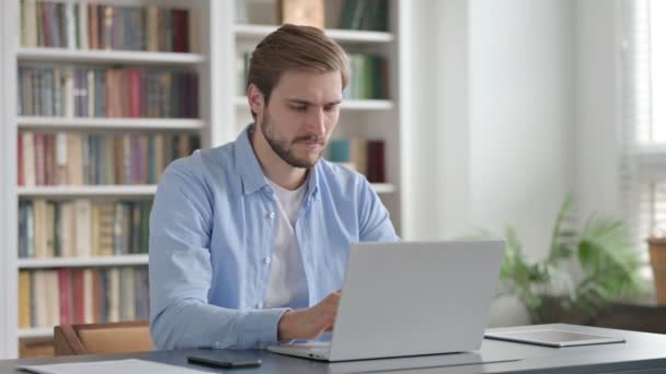 Uomo che punta alla fotocamera durante l'utilizzo del computer portatile in ufficio — Video Stock