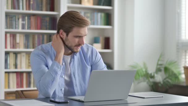 Hombre que tiene dolor de cuello mientras escribe en el ordenador portátil — Vídeo de stock