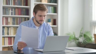 Dizüstü bilgisayar kullanırken Adam Belgeleri Okuyor 