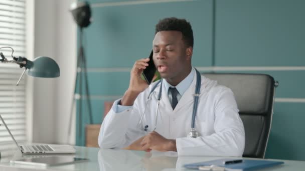 Médico Africano Falando em Smartphone enquanto trabalhava no laptop — Vídeo de Stock