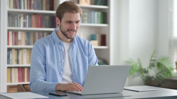 Hombre hablando en videollamada en el ordenador portátil en la oficina — Vídeo de stock