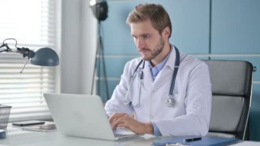 İşyerinde dizüstü bilgisayar kullanırken Başparmakları Aşağı İşaretini Gösteren Doktor