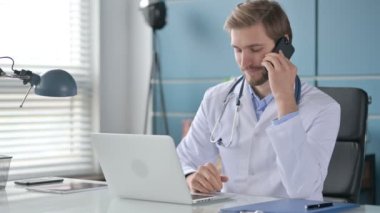 Bilgisayar üzerinde çalışırken, Doktor Smartphone 'da Konuşuyor