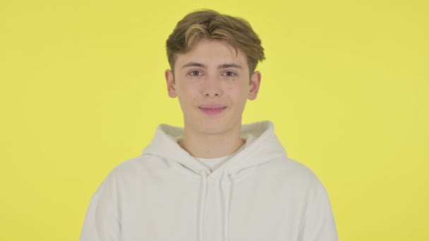 Молодий чоловік посміхається на камеру на жовтому тлі — стокове відео