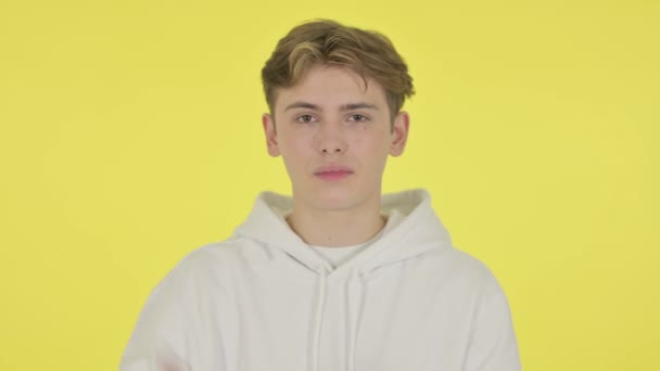 若い男は黄色の背景に指で兆候を示さない — ストック動画