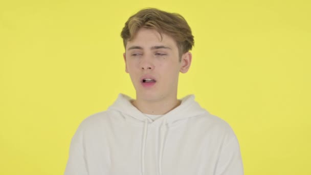 Молодой человек зевает на желтом фоне — стоковое видео