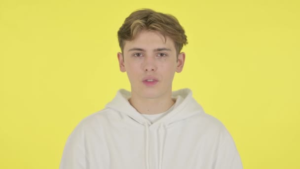 Молодой человек показывает стоп-знак на желтом фоне — стоковое видео