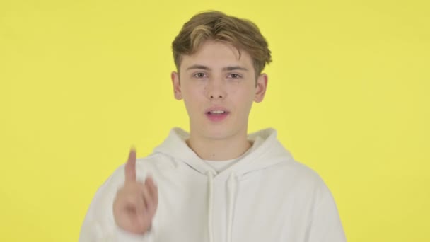 Junger Mann zeigt auf gelben Hintergrund in die Kamera — Stockvideo