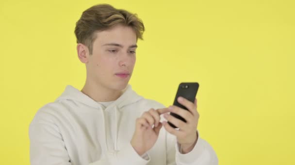 Joven celebrando en Smartphone sobre fondo amarillo — Vídeos de Stock