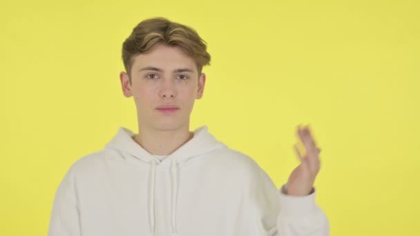 黄色の背景に手に製品を示す若い男 — ストック動画