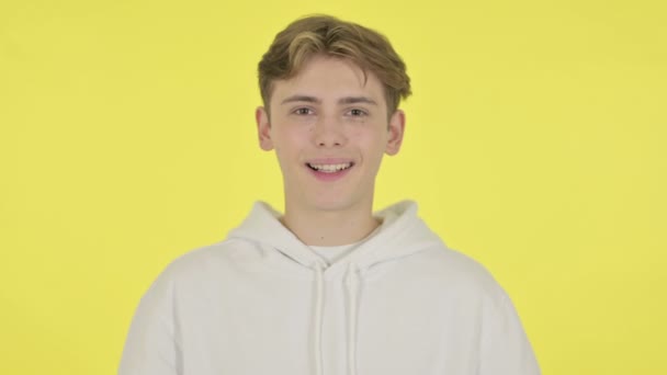 Jongeman toont hart vorm door handen op gele achtergrond — Stockvideo