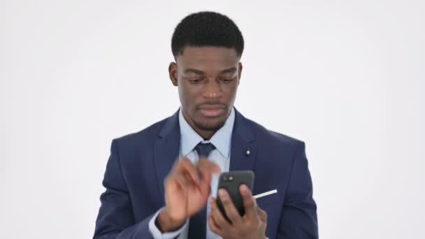 Empresario africano celebrando en Smartphone sobre fondo blanco — Vídeos de Stock