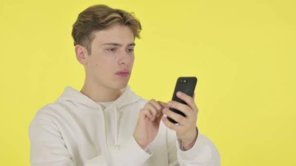 Joven Pérdida en Smartphone sobre fondo amarillo — Vídeos de Stock