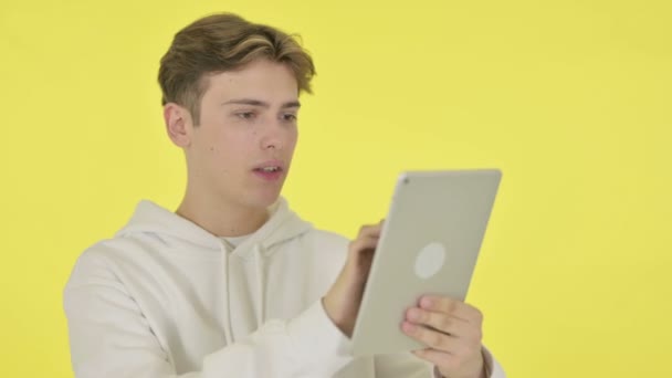 Hombre joven reaccionando a la pérdida en la tableta sobre fondo amarillo — Vídeos de Stock