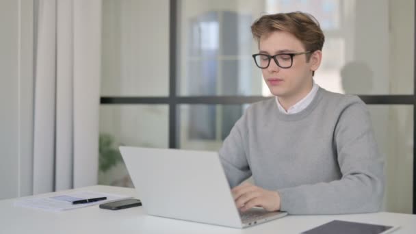 Ung man pekade på kameran när du använder laptop i moderna kontor — Stockvideo