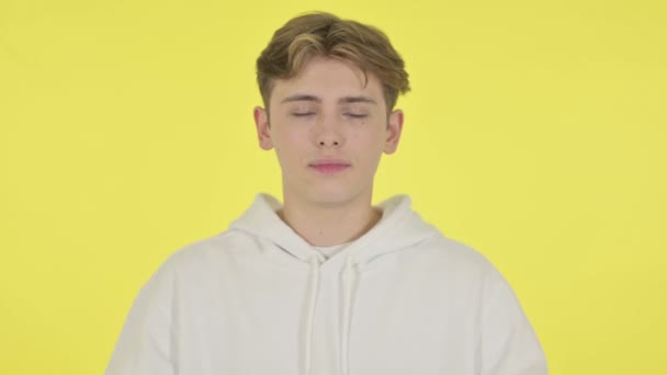 Junger Mann betet mit gekreuzten Fingern auf gelbem Hintergrund — Stockvideo