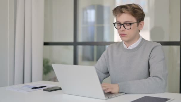 Mladý muž třese hlavou jako Ano podepsat při používání notebooku v moderní kanceláři — Stock video