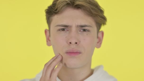Молодой человек с зубной болью на желтом фоне — стоковое видео