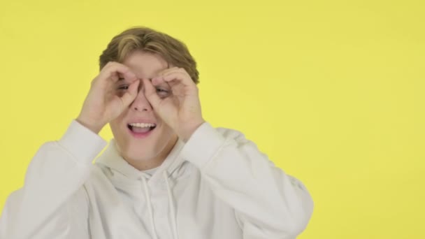 Jovem procurando com binocular artesanal na tela amarela — Vídeo de Stock