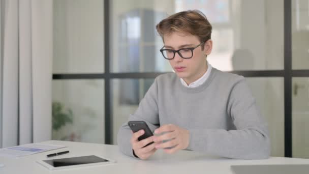 Attraktiv ung man som använder smartphone i moderna kontoret — Stockvideo