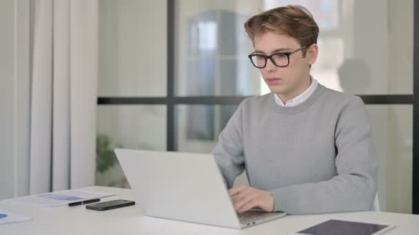 Joven hombre que cierra el ordenador portátil y deja la oficina moderna — Vídeo de stock