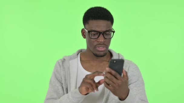 Perdita di uomo africano su smartphone su sfondo verde — Video Stock
