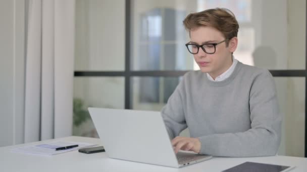 Unge mann hoster mens han bruker Laptop i det moderne kontoret – stockvideo