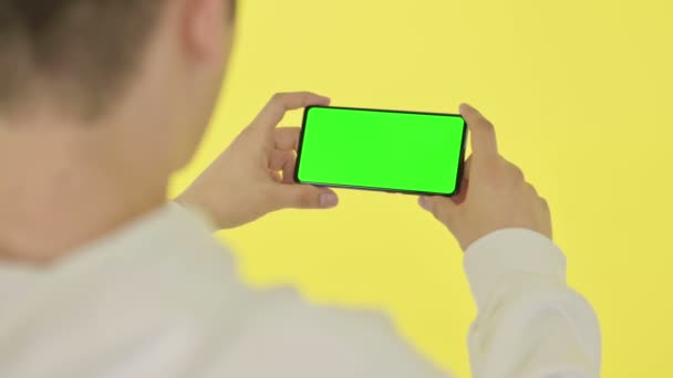 Horizontales Smartphone mit grünem Bildschirm, gelbem Hintergrund — Stockvideo