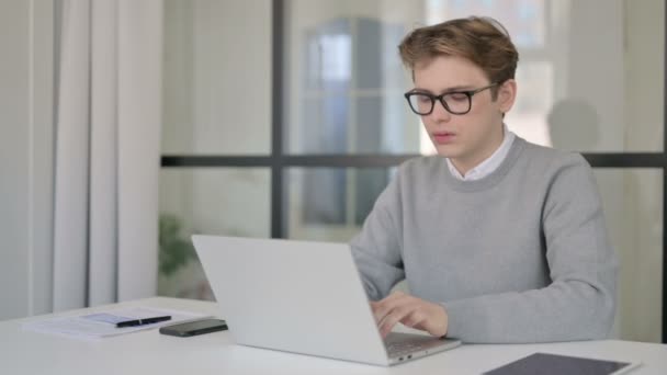 Ung man som reagerar på förlust när du använder laptop i moderna kontor — Stockvideo