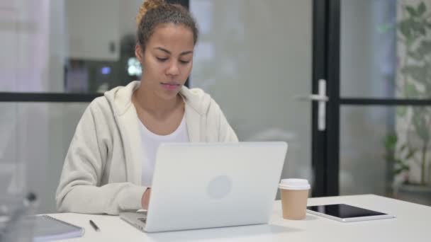 Afrikaanse vrouw glimlachen op camera tijdens het gebruik van laptop in Office — Stockvideo
