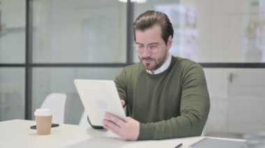 Ofiste otururken Tablet kullanan Genç İşadamı
