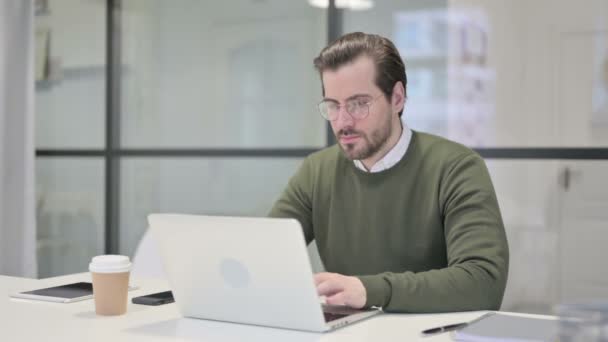 Jovem empresário sentindo-se chocado ao usar o laptop no escritório — Vídeo de Stock