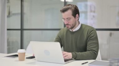 Ofiste Dizüstü bilgisayarda çalışan genç iş adamı.