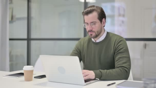 Jovem empresário com dor de pulso ao usar o laptop no escritório — Vídeo de Stock