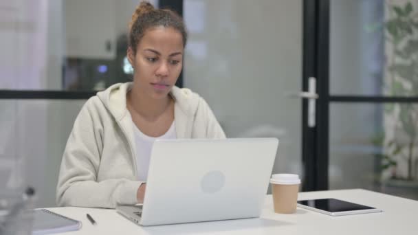 Mujer africana pensando mientras trabaja en el ordenador portátil en la oficina — Vídeos de Stock