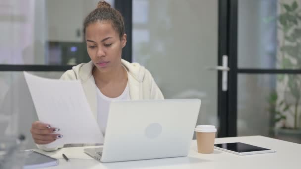 Afrikaanse vrouw met laptop lezende documenten in Office — Stockvideo