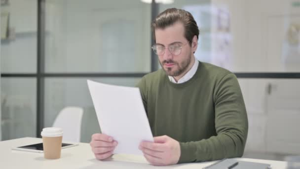 Νεαρός επιχειρηματίας Διαβάζοντας Αναφορές ενώ κάθεται στο γραφείο — Αρχείο Βίντεο
