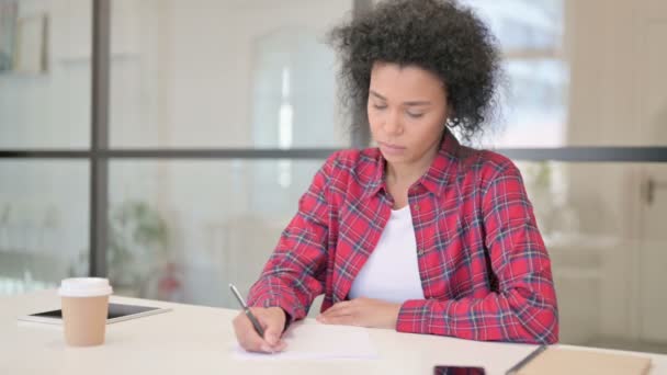 Африканська жінка пише на папері в офісі — стокове відео