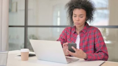 Laptop kullanırken Akıllı Telefon kullanan Afrikalı Kadın 