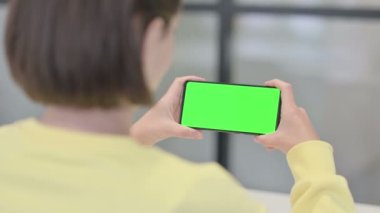 Yeşil ekranlı akıllı telefona bakan kadın