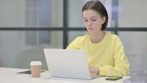 Молодая женщина качает головой без каких-либо признаков при использовании ноутбука в офисе — стоковое видео